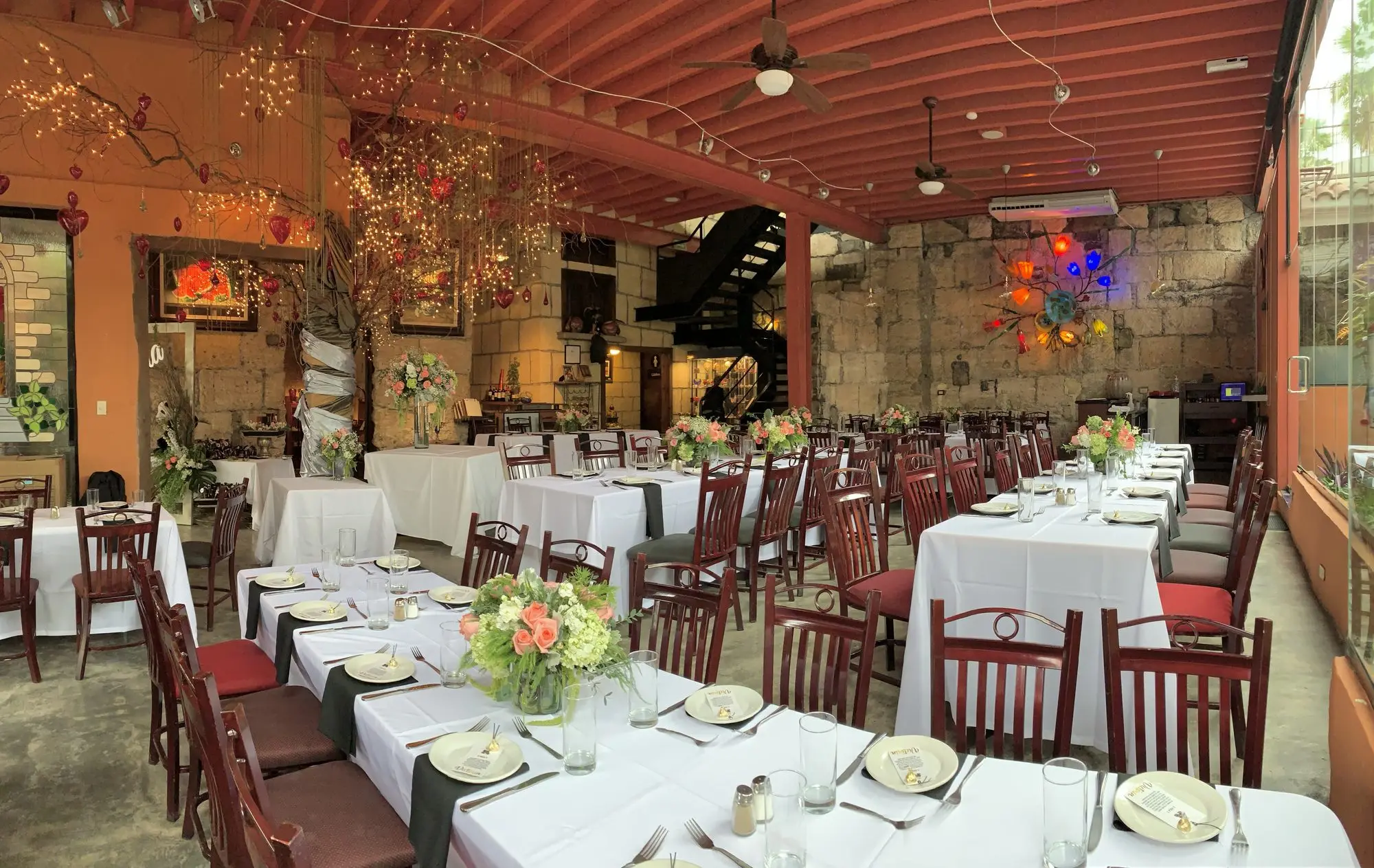 The Main Dining Room tables dressed in white, beside the stone wall