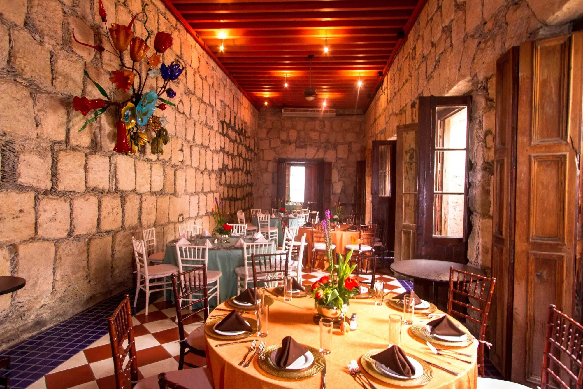 Salón Romancera set with round tables, under the red-beamed ceiling