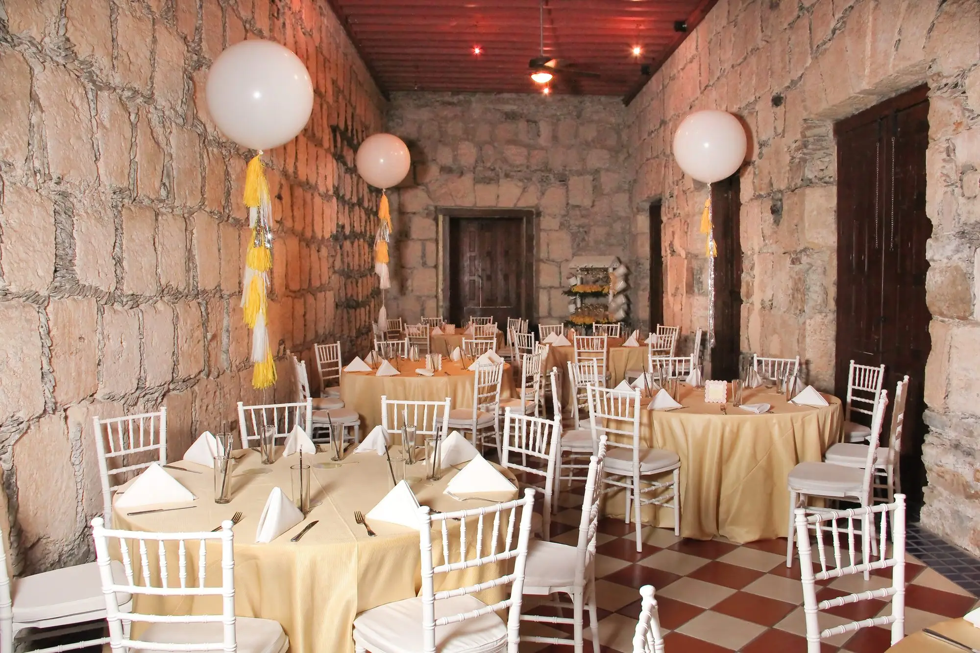 Salón Romancera set for a celebration, with balloons over the round tables
