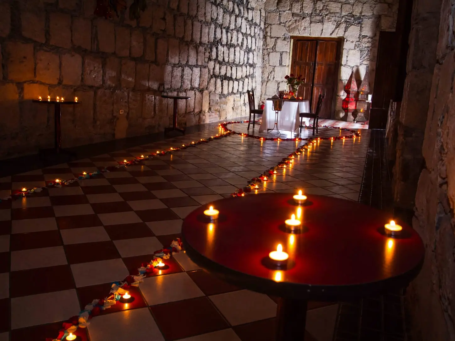 A path of candles across the checkerboard floor of Salón Romancera, with the lit table at the far end