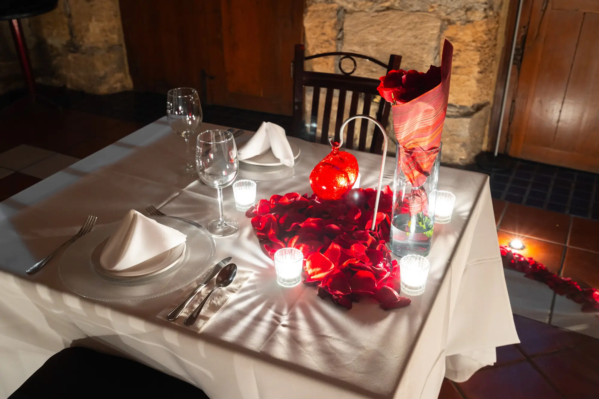 Rosas rojas y el corazón de cristal sobre el mantel blanco, en primer plano